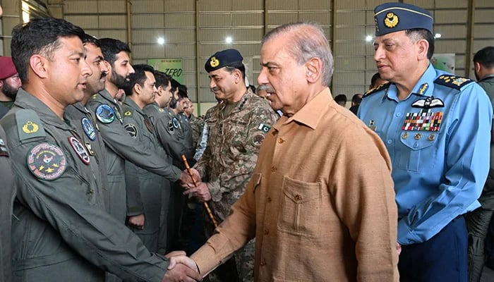 Prime Minister Shehbaz Sharif shakes hands with PAF pilots at the PAF operational base in Kamra on May 15, 2025. COAS General Syed Asim Munir and Chief of Air Staff Air Chief Marshal Zaheer Ahmed Baber Sidhu are also present.