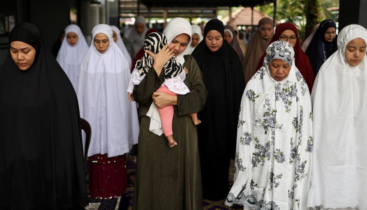 A Muslim woman carries a toddler as she performs Eid ul Adha mass prayers at a mosque in Ampang, Malaysia, May 27, 2026. — Reuters