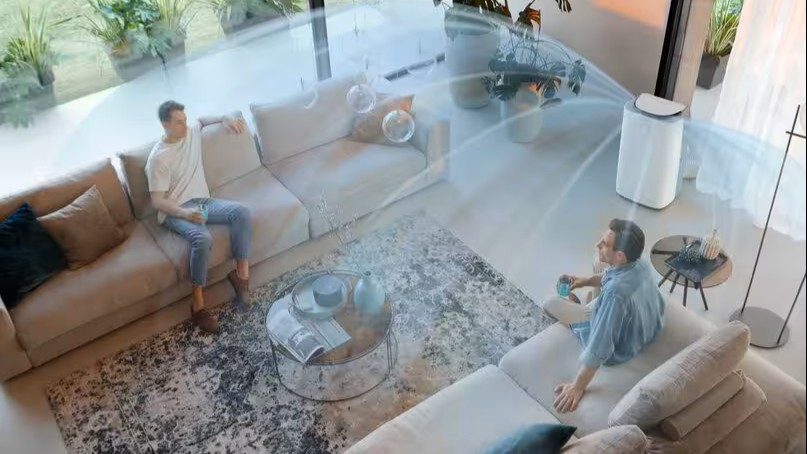 De'Longhi air conditioner in a room with two people and lines representing air movement
