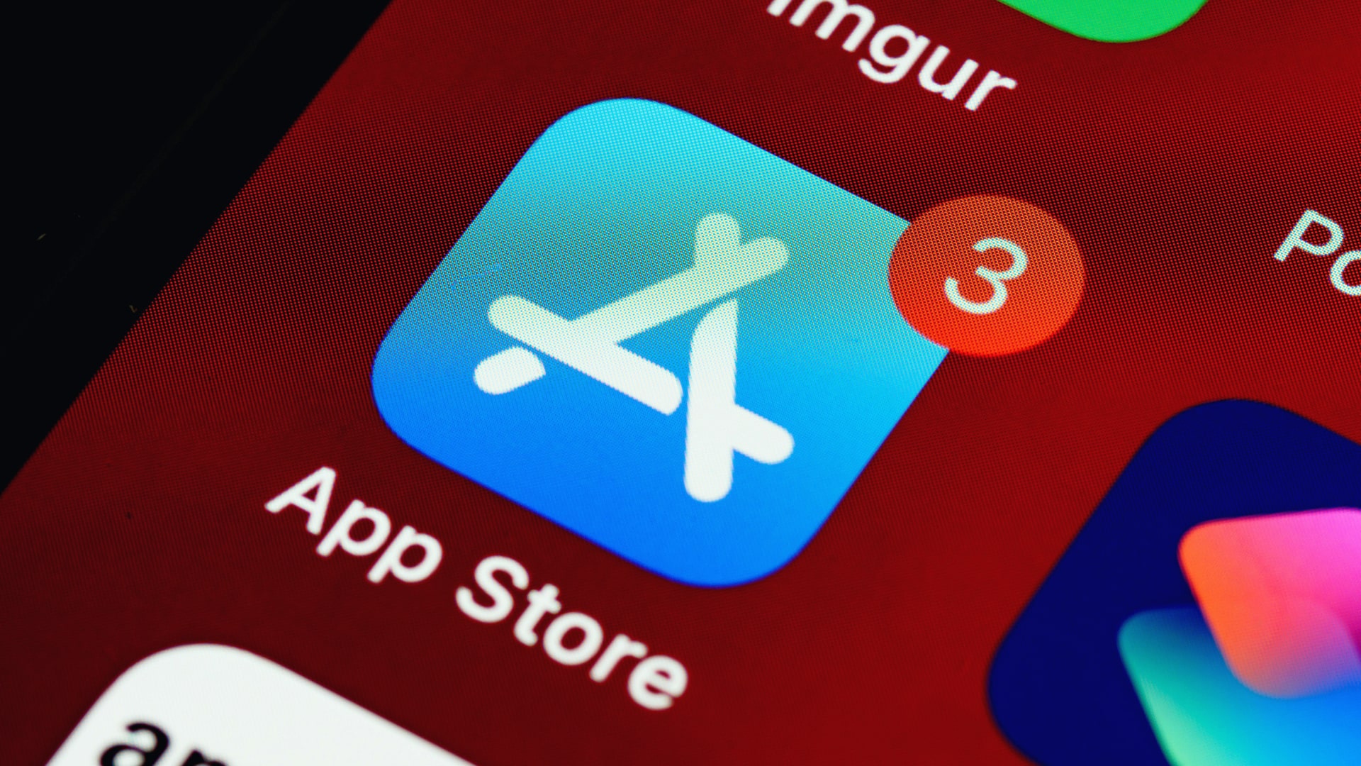 A close-up photo of an iPhone, with the App Store icon clearly visible in the center of the image.