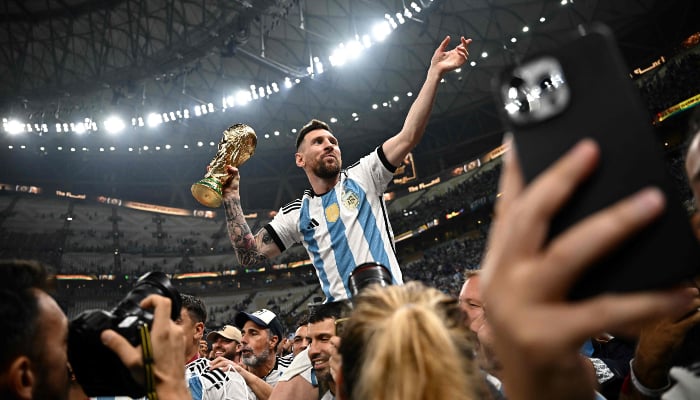 Argentina captain and striker Lionel Messi (right) holds the FIFA World Cup trophy after the trophy ceremony after Argentina won the Qatar 2022 World Cup final between Argentina and France at Lusail Stadium in Lusail, north of Doha, on December 18, 2022. — AFP