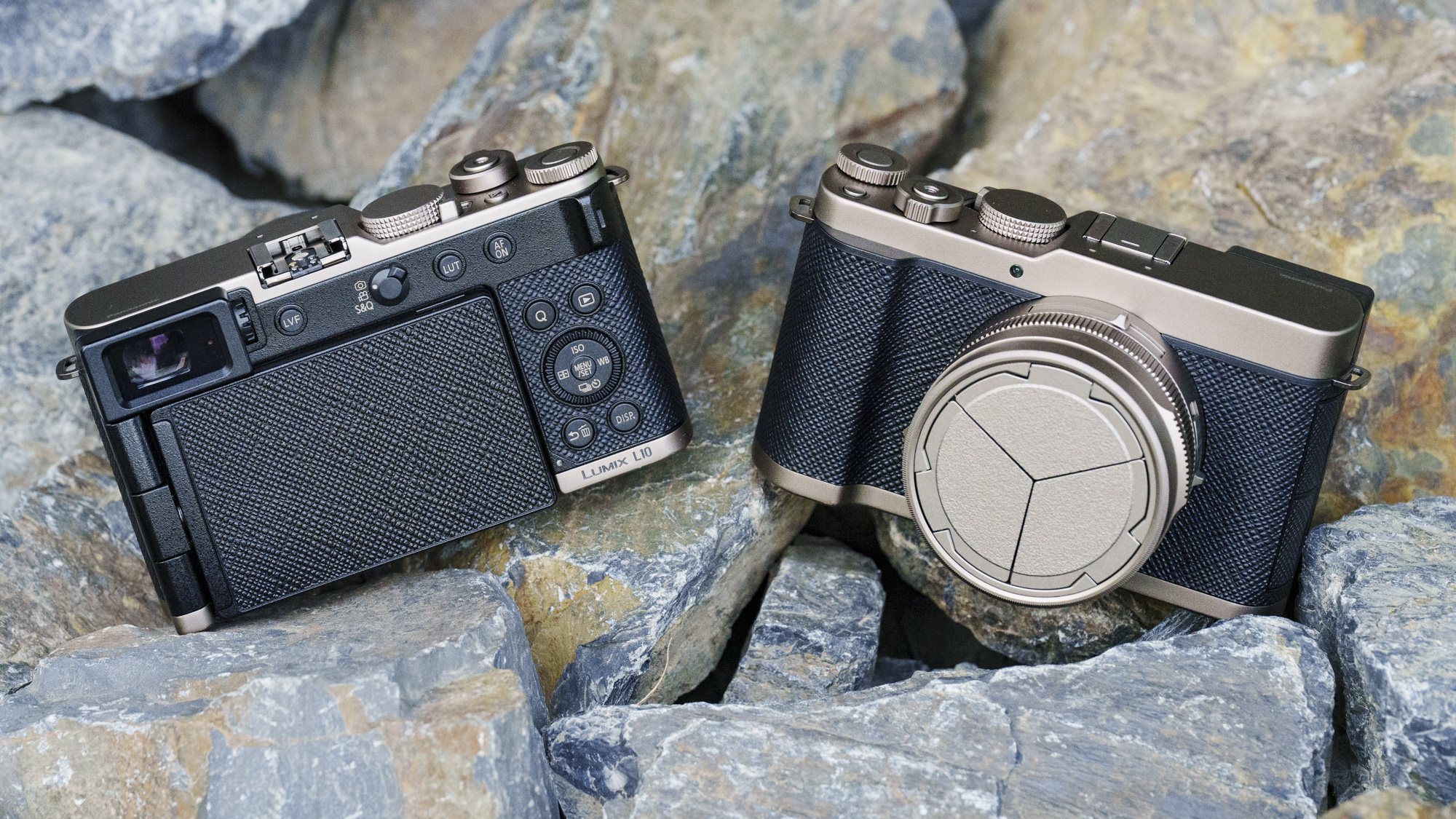 The Gold Titanium special edition of the Panasonic Lumix L10 compact camera, lying on gray and rust rocks