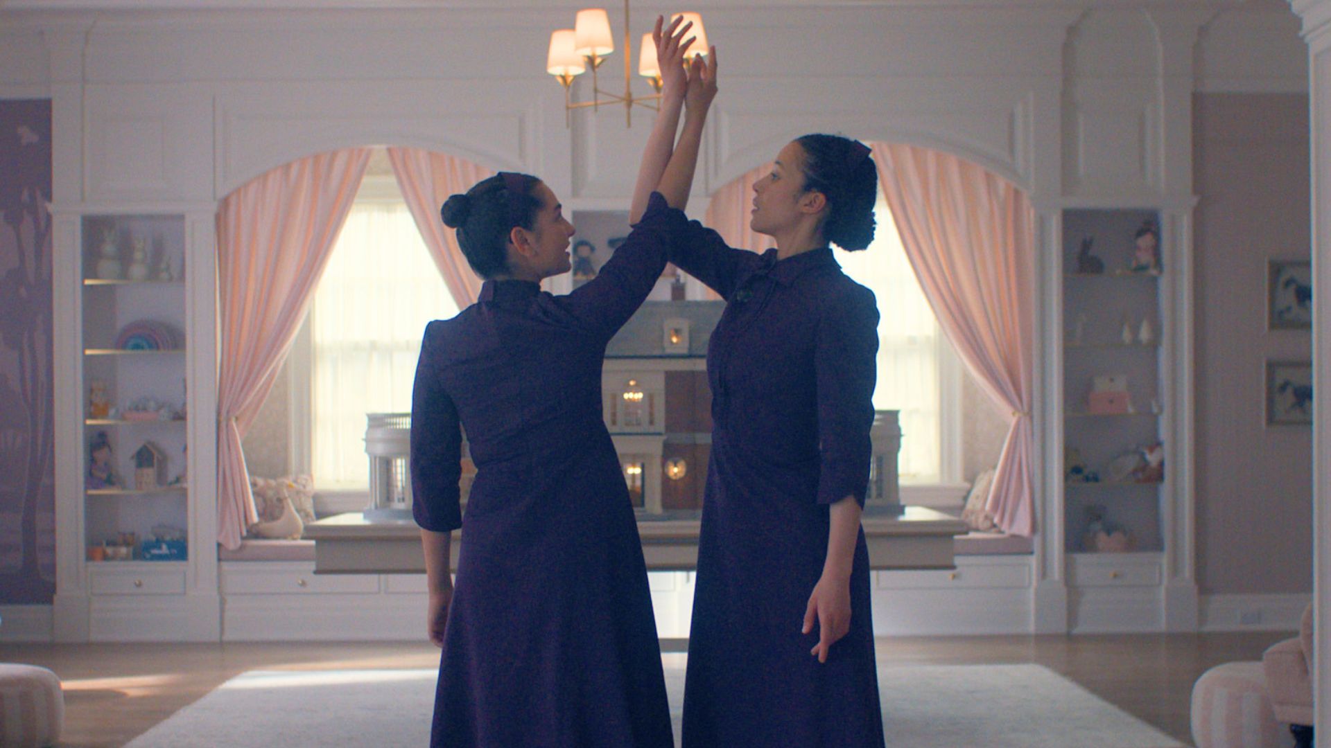 Two girls dressed in plum dance in the middle of a room