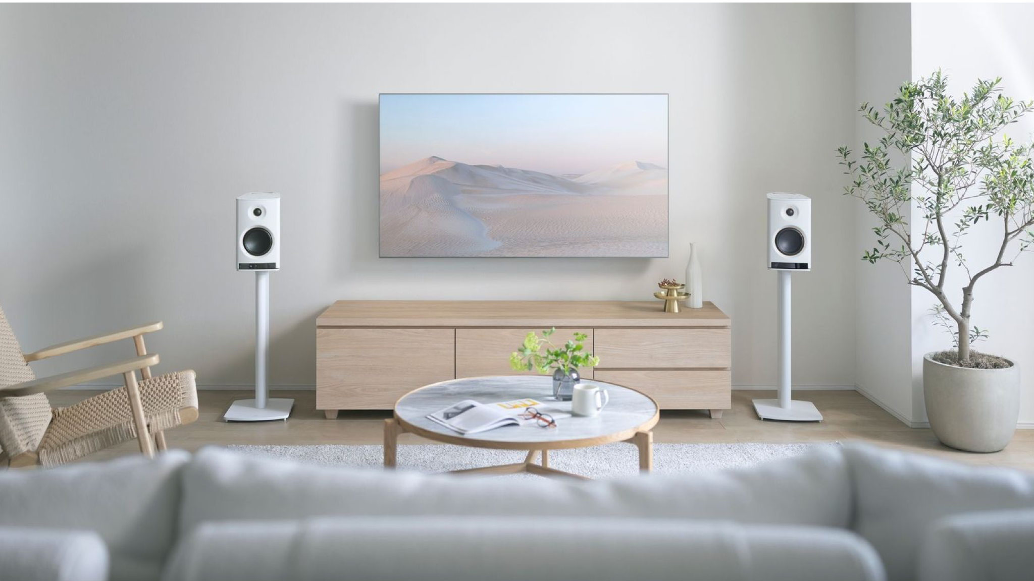 Yamaha NX-70A speakers in white in a neutrally decorated, well-lit room. They are on stands on either side of a wall-mounted TV.