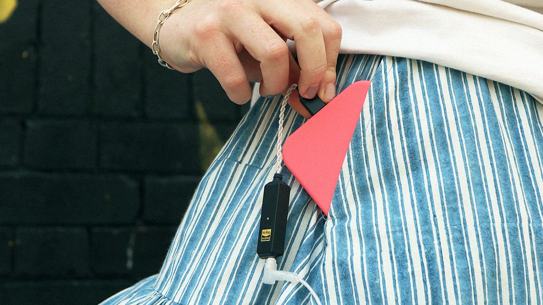 iFi Go Link 2 Max coming out of a woman's pocket, with a phone connected
