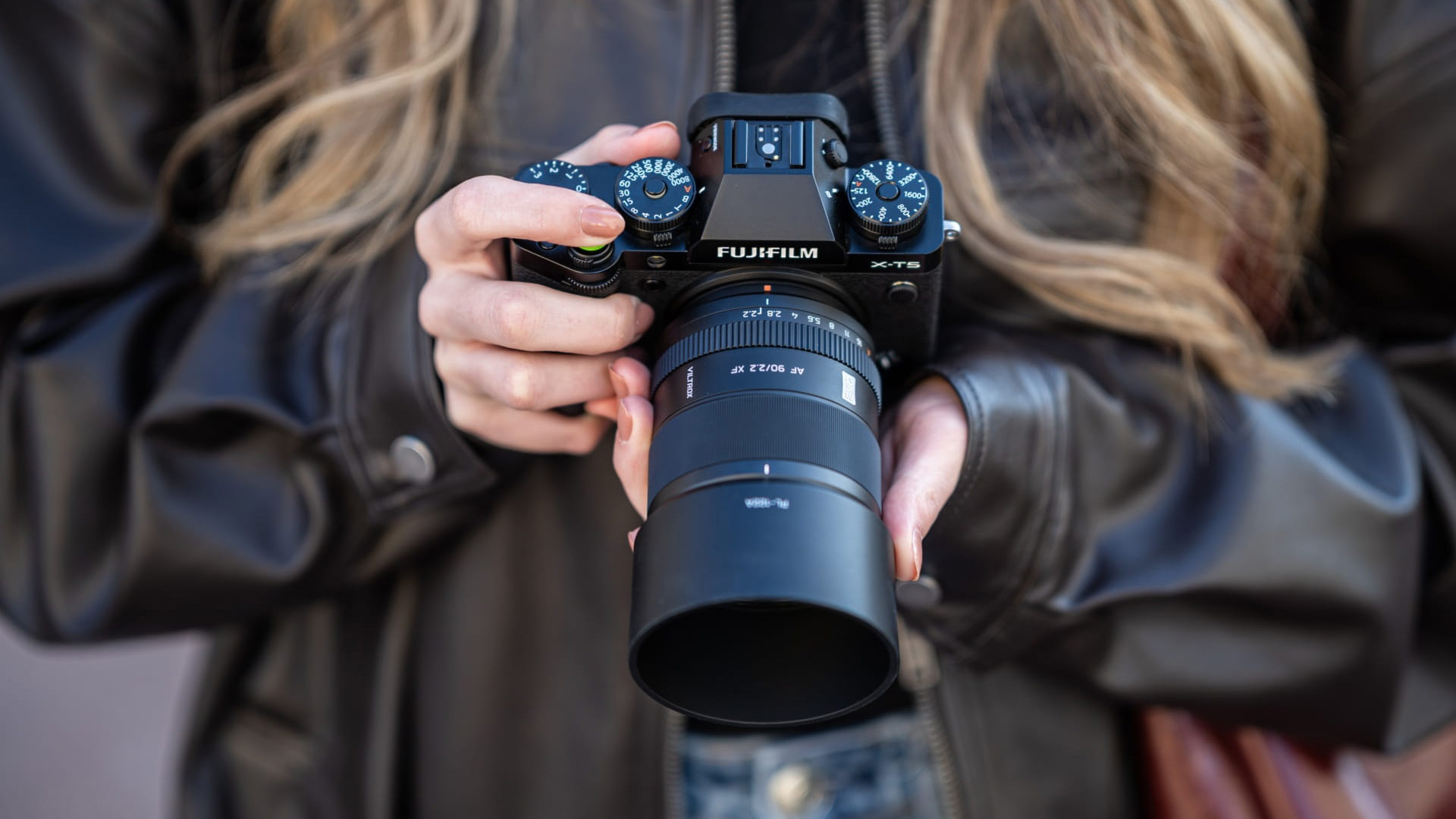 The Viltrox AF 75mm F1.8 EVO lens attached to a Fujifilm camera, held down by a photographer