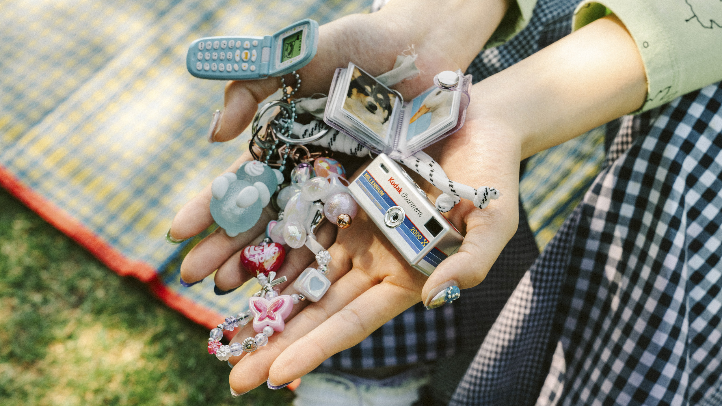 A Kodak Charmera Millennium Edition camera in the person's hands, alongside other Y2K-inspired trinkets
