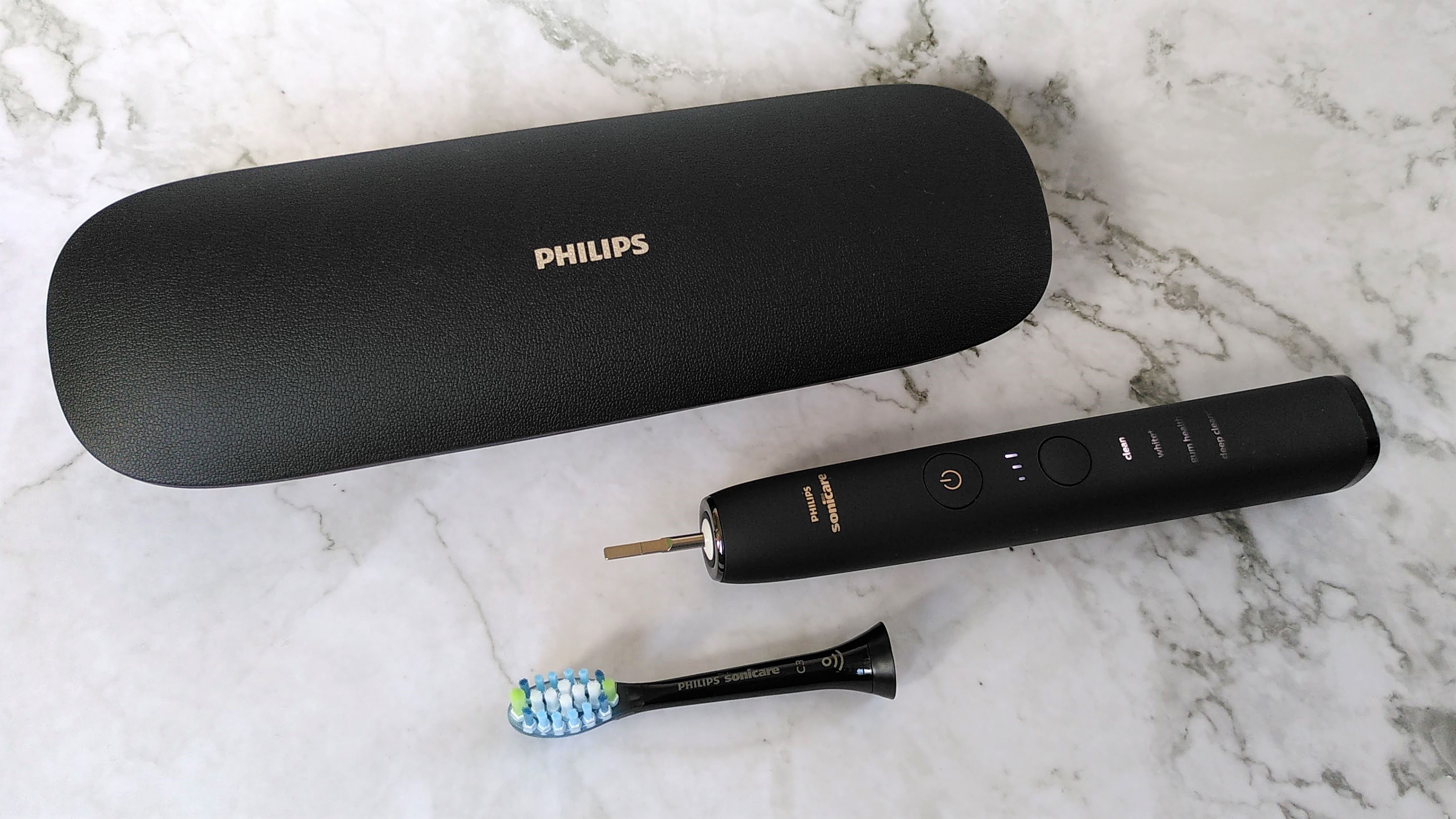 Philips Sonicare 9000 DiamondClean with detached brush head, next to charging case