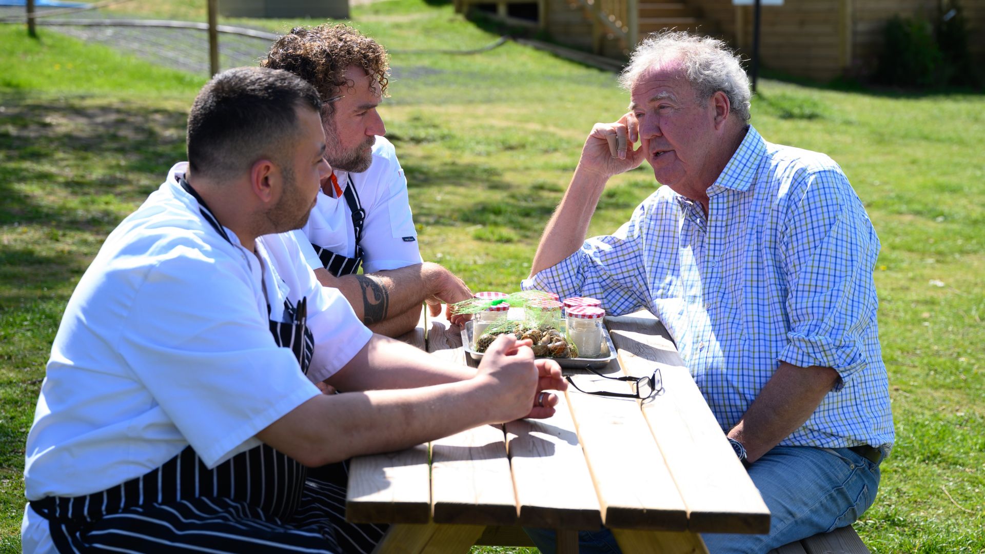 Jeremy talks to two chefs around a picnic table