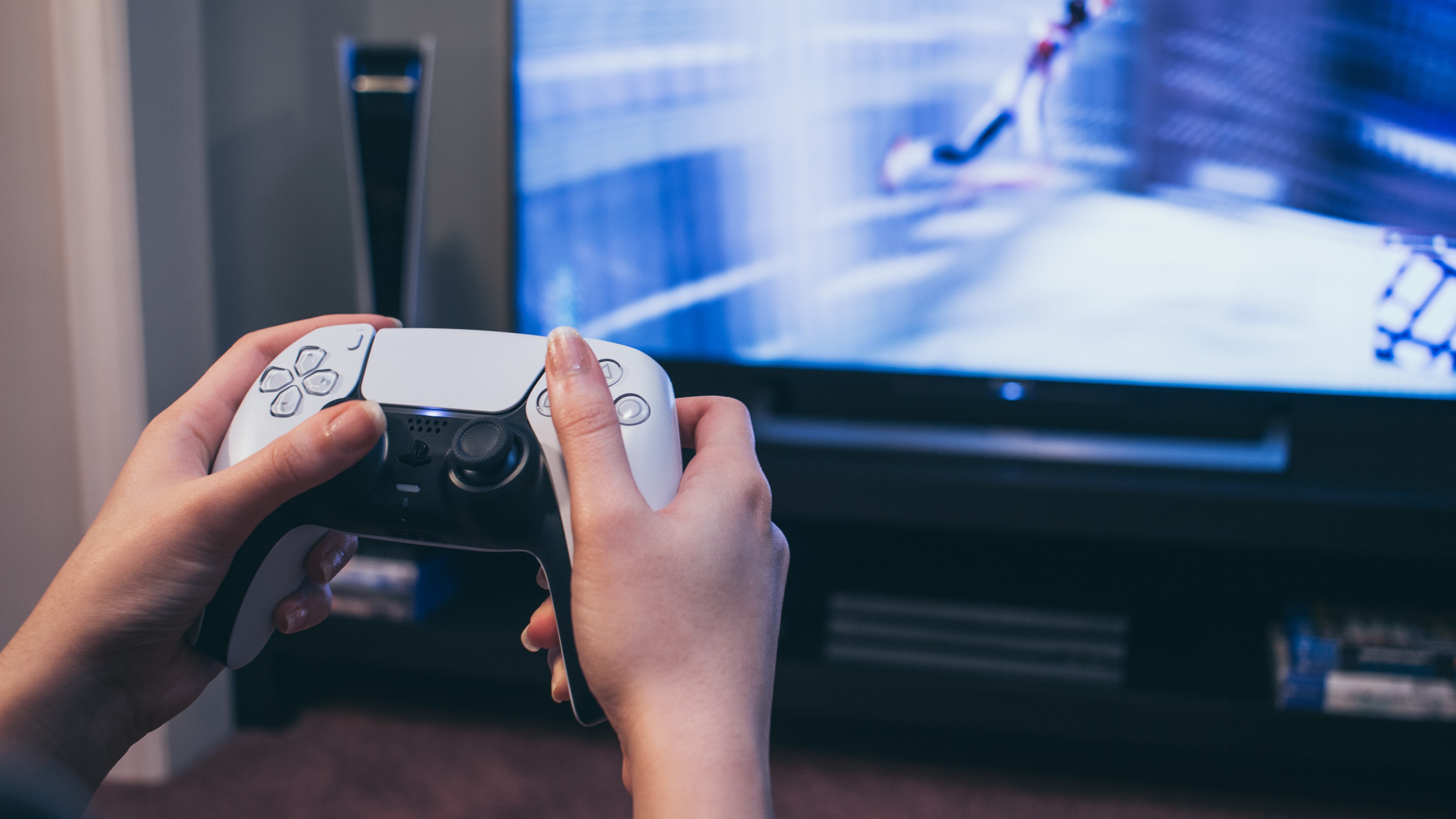 Person playing PS5 games on a TV with a DualSense wireless controller