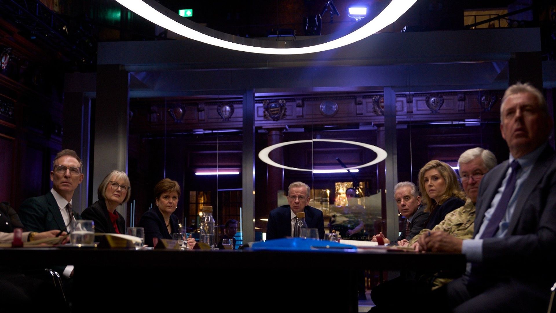 A fake government cabinet sits around a meeting table
