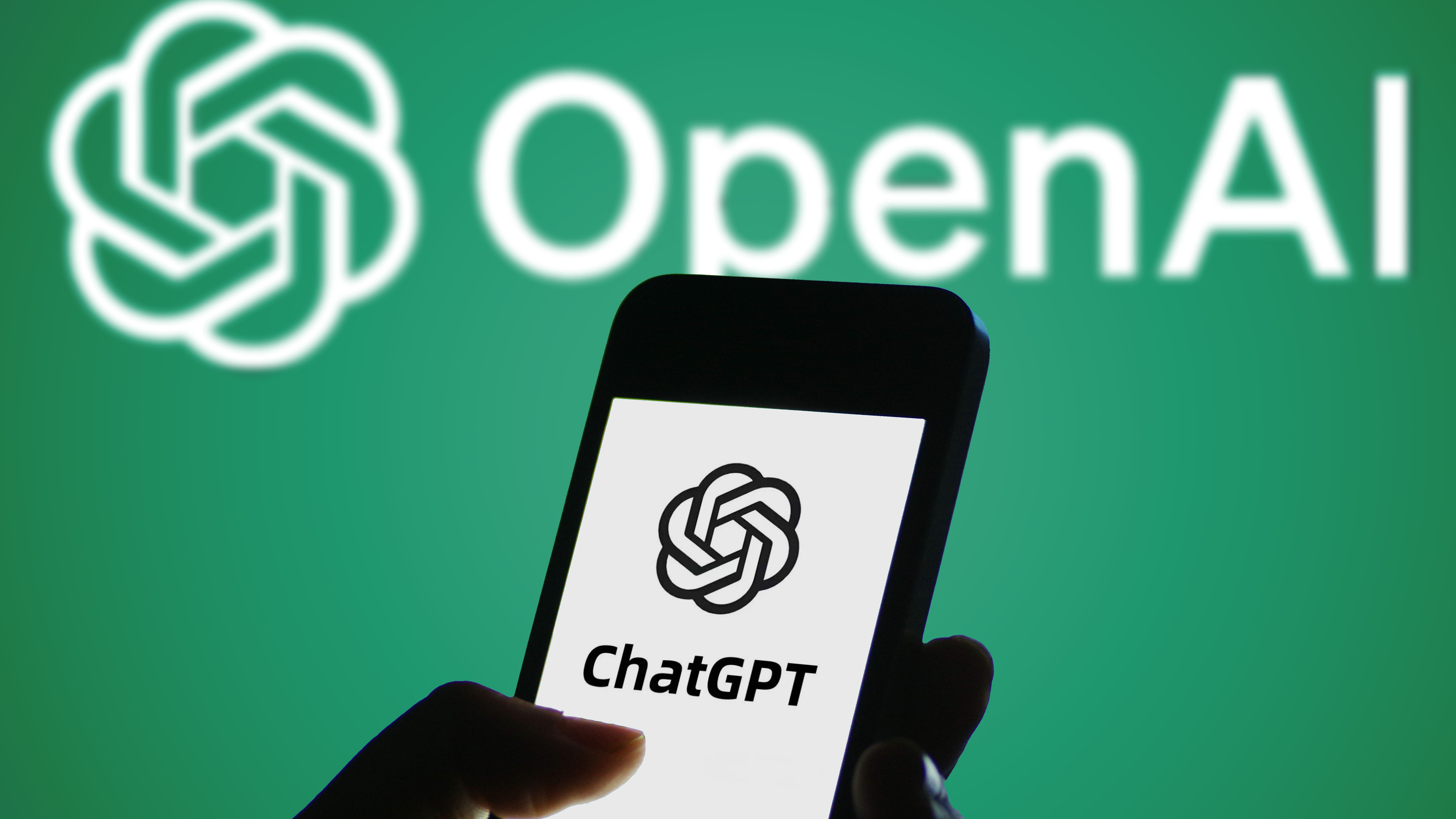 In this photo illustration, the ChatGPT logo is displayed on a smartphone screen with an OpenAI logo in the background.
