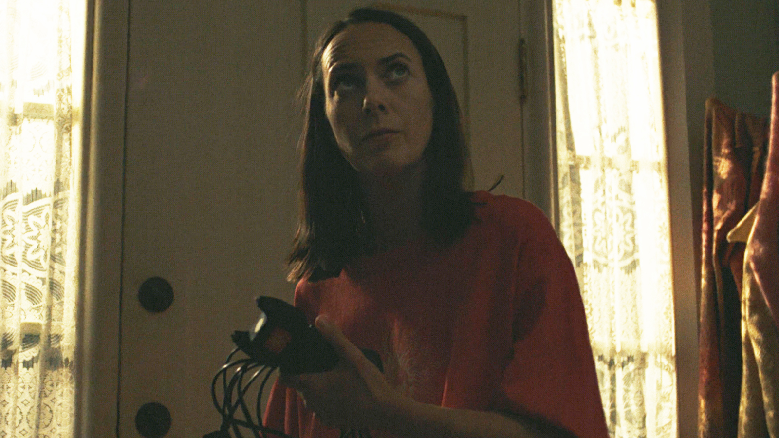 Patricia holding a tazer and her charging cable in her house at night in Widow's Bay episode 8