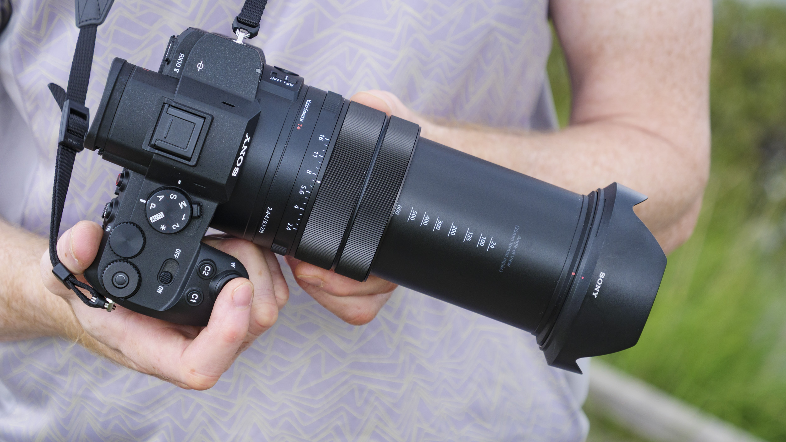 Photographer and tech journalist Tim Coleman holds Sony RX10 V bridge camera, its lens zoomed out