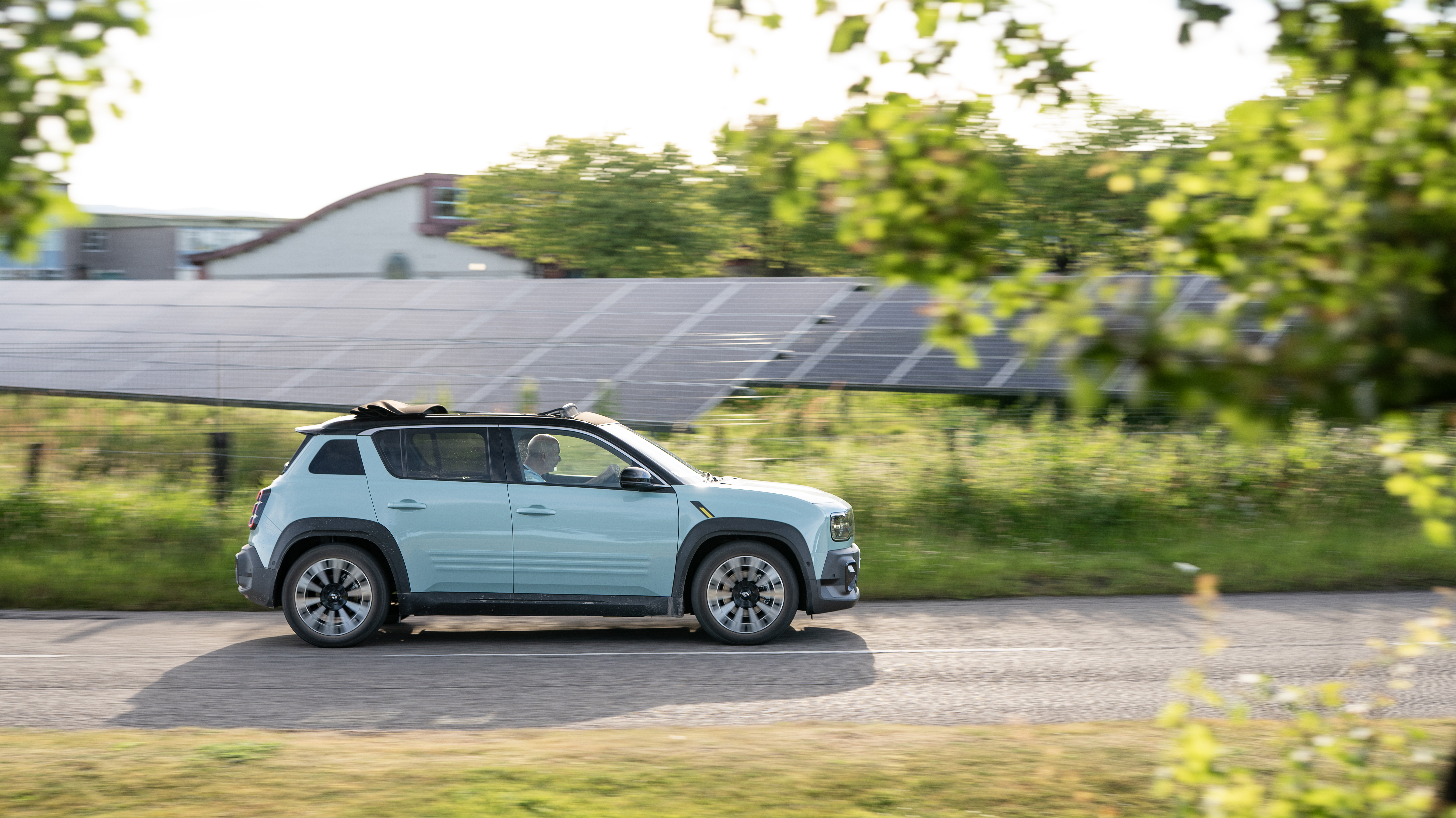 An electric car driving in front of a solar farm