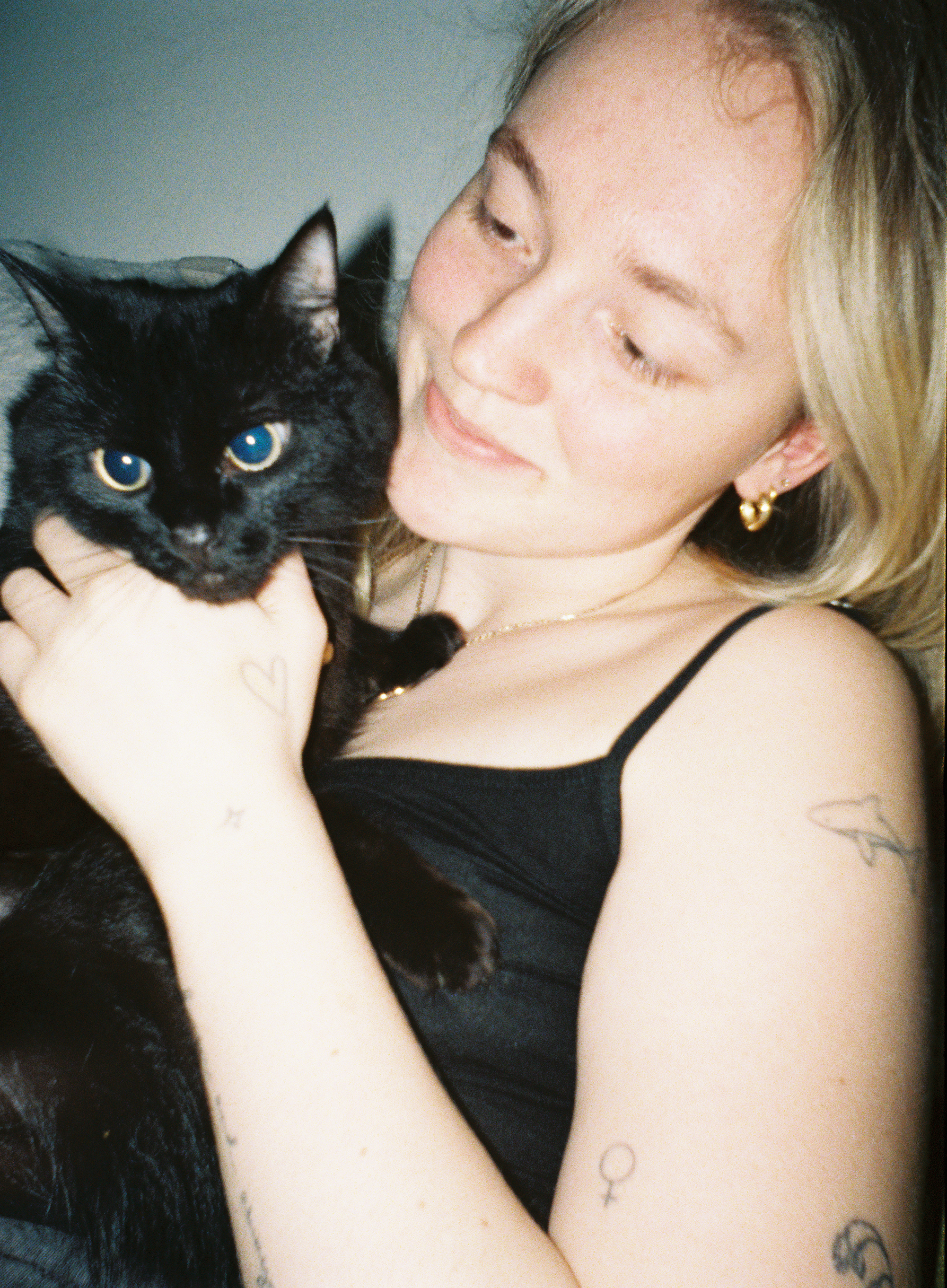 Example image from a Lomography single-use half-frame rechargeable film camera showing a woman holding a black cat, lit by a flash