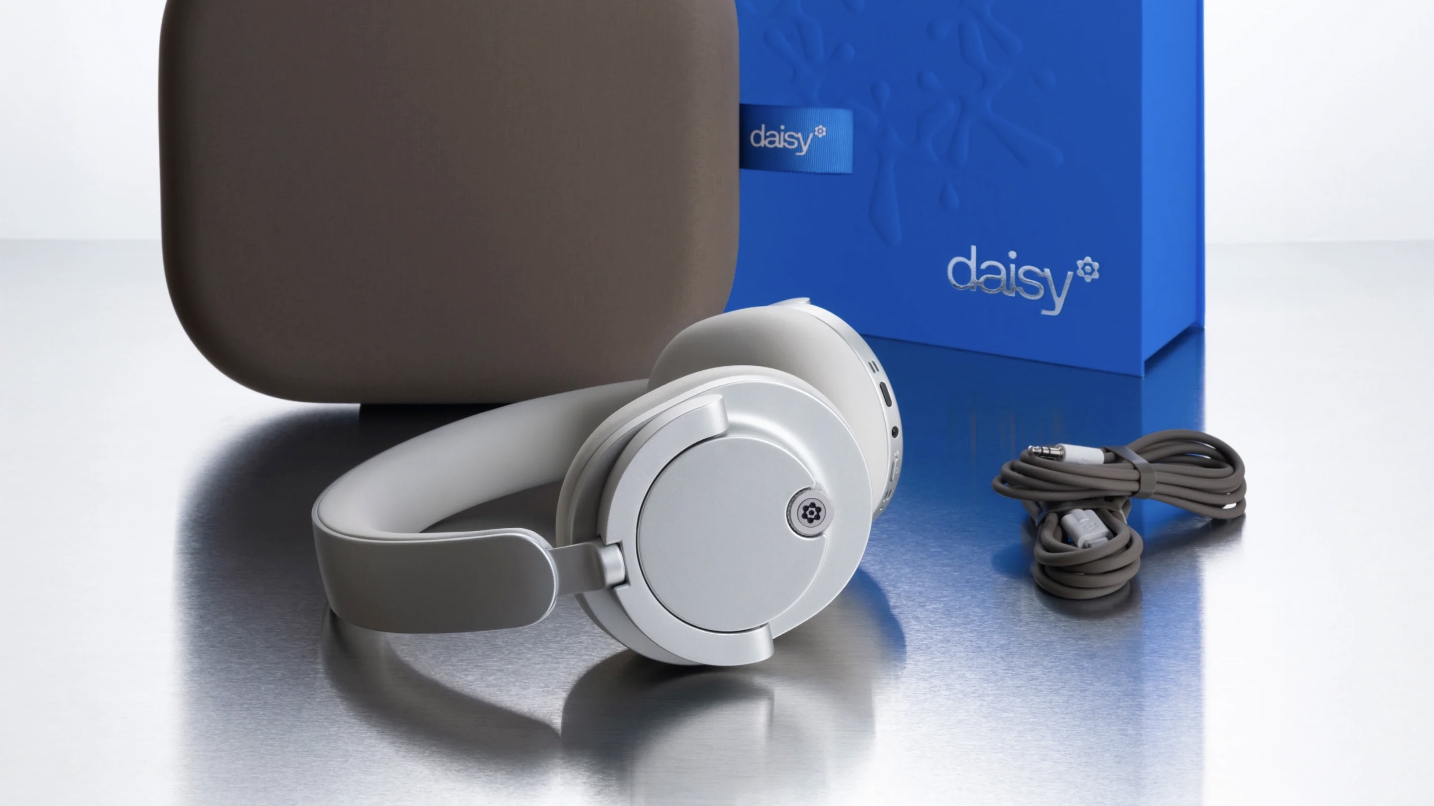 The Daisy One headphones in front of their case, cables and box.