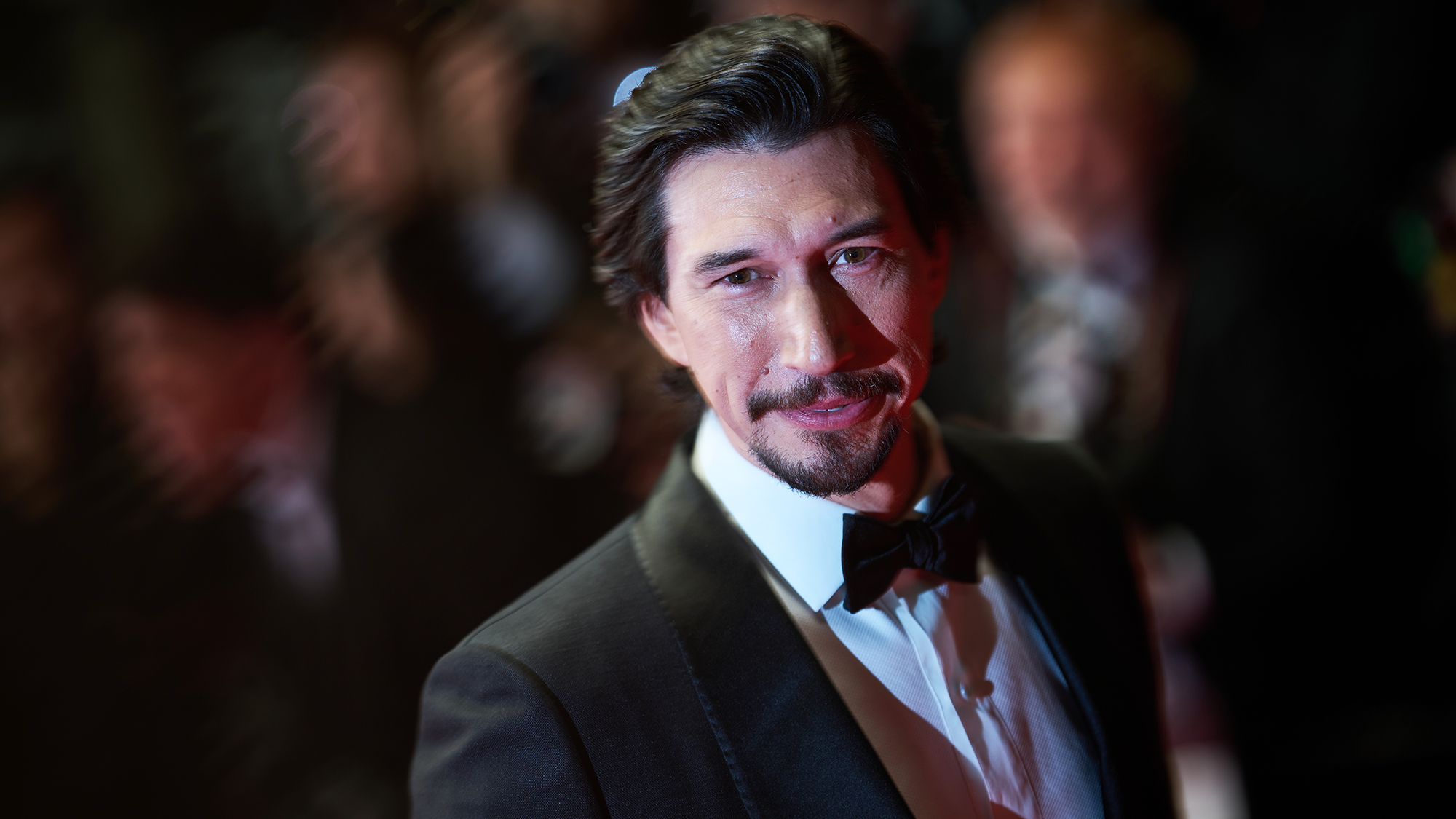 Adam Driver smiling while wearing a tuxedo at an event